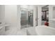 Modern bathroom featuring glass shower, gray tiled walls, white fixtures, and a view into the bedroom at 9567 Meadow Hunt Way, Winter Garden, FL 34787