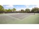 Well-maintained tennis courts enclosed with a dark fence and surrounded by lush trees under a sunny sky at 9567 Meadow Hunt Way, Winter Garden, FL 34787