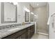 Bathroom with granite countertops, dual sinks, dark cabinets, and glass-enclosed shower at 9820 Bucklow Hill Dr, Orlando, FL 32832