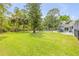 Large, grassy backyard with mature trees, a swimming pool, and patio furniture for outdoor relaxation at 106 Pine Tree Dr, Ormond Beach, FL 32174
