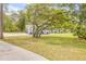 Well-manicured front yard featuring a mature tree, colorful landscaping, and a charming home exterior at 106 Pine Tree Dr, Ormond Beach, FL 32174