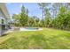 Inviting backyard pool surrounded by green grass and mature trees offers a serene outdoor experience at 106 Pine Tree Dr, Ormond Beach, FL 32174