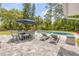 Beautiful pool area with a patio table, lounge chairs, and a large blue umbrella for shade and relaxation at 106 Pine Tree Dr, Ormond Beach, FL 32174