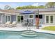 Step into the pool from the patio, featuring solar panels and lounge chairs for a luxurious backyard experience at 106 Pine Tree Dr, Ormond Beach, FL 32174