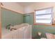 Bathroom featuring a walk-in tub, green tile, and large window at 1108 Gibson St, Leesburg, FL 34748