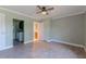 Bedroom view with gray laminate flooring and ceiling fan, doorway to laundry room and bathroom at 1108 Gibson St, Leesburg, FL 34748