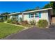 Side view of this single story home with white brick, bright blue shutters, a lush yard, and landscaped flowerbeds at 1118 Ne 17Th Ave, Ocala, FL 34470