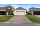 View of a detached two-car garage with brick driveway and manicured lawn at 11386 Biography Way, Orlando, FL 32832