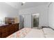 Bright bedroom featuring a wooden dresser, a television and an ensuite bathroom with glass enclosed shower at 1611 Creekwood Run, Lakeland, FL 33809