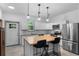 Modern kitchen featuring stainless steel appliances, white cabinets, an island with chairs, and sleek light fixtures at 1611 Creekwood Run, Lakeland, FL 33809