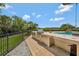 An outdoor kitchen with stainless steel grill and a pool with small waterfall feature at 1710 Bridgets Ct, Kissimmee, FL 34744