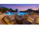 A fire pit with outdoor seating near the pool featuring palm trees and waterfalls at dusk at 1710 Bridgets Ct, Kissimmee, FL 34744