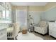 Sunlit Bedroom showcasing a white crib, soft textures, a comfortable chair, and playful decor accents at 203 Taylor Groves Dr, Lake Wales, FL 33853
