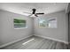 Bedroom with gray walls, wood-look flooring, ceiling fan and natural light from the two windows at 2105 9Th Ne St, Winter Haven, FL 33880