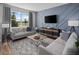 Comfortable living room featuring a sofa, entertainment center, and natural light through a large window at 3173 Douglas Fir Dr, Apopka, FL 32703
