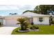 Charming single-story home with well-manicured lawn, lovely shrubbery, and a pink accent on the shutters and garage door at 32900 Crooked Oaks Ln, Leesburg, FL 34748