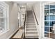 Bright foyer features wood floors, staircase, and view of a home office through glass-paned French doors at 3647 Farm Bell Pl, Lake Mary, FL 32746