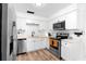 Bright kitchen featuring stainless steel appliances, white cabinets, light countertops, and wood-look floors at 376 Orange Ave, Longwood, FL 32750