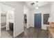 Hallway with wood-look flooring leading to a bathroom and an office area, featuring a gray accent door at 4599 Storytelling Way, Kissimmee, FL 34746