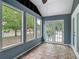 View of a tiled-floor screened porch featuring large windows, a ceiling fan, and double doors at 499 W Beresford Rd, Deland, FL 32720