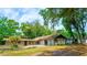 Sprawling single-story home with mature trees, a covered patio, and a well-manicured lawn, offering a serene outdoor experience at 530 Webster St, Lake Mary, FL 32746