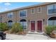 Charming townhome featuring arched windows, red doors, and well-maintained landscaping at 611 Casa Park A Ct, Winter Springs, FL 32708