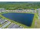 Aerial view of a Primary-planned community featuring homes bordering a lake with lush wooded areas in the distance at 6121 Blue Pond Way, St Cloud, FL 34771