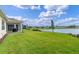 Expansive backyard with lush green grass leading to a serene lake, with a screened-in lanai at 6121 Blue Pond Way, St Cloud, FL 34771
