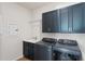 Laundry room with front-load washer/dryer, sink, and stylish navy blue cabinets at 6121 Blue Pond Way, St Cloud, FL 34771