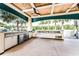 Outdoor amenity covered kitchen featuring stainless steel appliances, plenty of counter space, and beautiful landscaping at 6121 Blue Pond Way, St Cloud, FL 34771