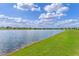 Picturesque lake surrounded by lush green lawns and homes under a sunny, cloudy sky at 6121 Blue Pond Way, St Cloud, FL 34771