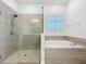 Elegant bathroom showcases a glass-enclosed shower and separate soaking tub near a window at 7398 Alpine Butterfly Ln, Orlando, FL 32819