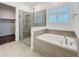 Stylish bathroom with glass-enclosed shower and a separate tub under a shuttered window at 7398 Alpine Butterfly Ln, Orlando, FL 32819