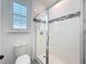 Bathroom featuring tiled shower with glass door and a white toilet, and shuttered window at 7398 Alpine Butterfly Ln, Orlando, FL 32819