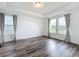 Spacious bedroom featuring wood flooring, tray ceiling, and multiple windows with peaceful neighborhood views at 7398 Alpine Butterfly Ln, Orlando, FL 32819