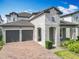 Inviting two-story home boasts a two-car garage, brick driveway, and lovely stone accents on the facade at 7398 Alpine Butterfly Ln, Orlando, FL 32819