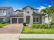 Charming two-story home featuring a two-car garage, brick driveway, and beautifully landscaped front yard at 7398 Alpine Butterfly Ln, Orlando, FL 32819