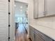 Hallway leading to kitchen, featuring gray cabinets, white countertops, stainless steel appliances and wood floors at 7398 Alpine Butterfly Ln, Orlando, FL 32819