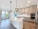 Kitchen with stainless steel appliances, gray cabinets, an island with white countertop and modern pendant lighting at 7398 Alpine Butterfly Ln, Orlando, FL 32819