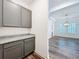 Mud room with gray cabinets, granite countertop, wood floors and a view of living area with plantation shutters at 7398 Alpine Butterfly Ln, Orlando, FL 32819