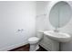 Powder room featuring a pedestal sink, round mirror, toilet and wood-look flooring at 7398 Alpine Butterfly Ln, Orlando, FL 32819