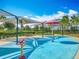 Community splash pad with covered seating, blue rubber surface, and colorful play features at 7398 Alpine Butterfly Ln, Orlando, FL 32819