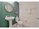 Stylish powder room with modern fixtures, including a pedestal sink, toilet, and palm tree artwork at 7564 Marker Ave, Kissimmee, FL 34747