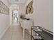 Hallway with white tile floors and neutral walls, featuring decorative art and a view to the backyard at 7564 Marker Ave, Kissimmee, FL 34747