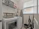 Functional laundry room with modern washer and dryer, storage shelves, and an ironing board at 7564 Marker Ave, Kissimmee, FL 34747