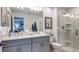 Bathroom featuring double sinks, gray cabinets, and glass-enclosed shower in a neutral color palette at 7751 Waterscape Dr, Groveland, FL 34736