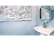 Stylish powder room with pedestal sink, round mirror, and blue walls at 7753 Waterscape Dr, Groveland, FL 34736