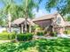 Charming two-story home features manicured landscaping, a two-car garage, and mature palm trees at 1007 Golf View Estates Dr, Orange City, FL 32763