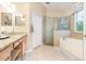 Bright bathroom with granite counters, double sink, and a separate glass enclosed shower and soaking tub at 10222 Marsh Pine Cir, Orlando, FL 32832