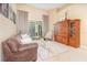 Cozy living room featuring neutral decor, comfortable seating, sliding glass doors to the lanai, and wood entertainment center at 10222 Marsh Pine Cir, Orlando, FL 32832